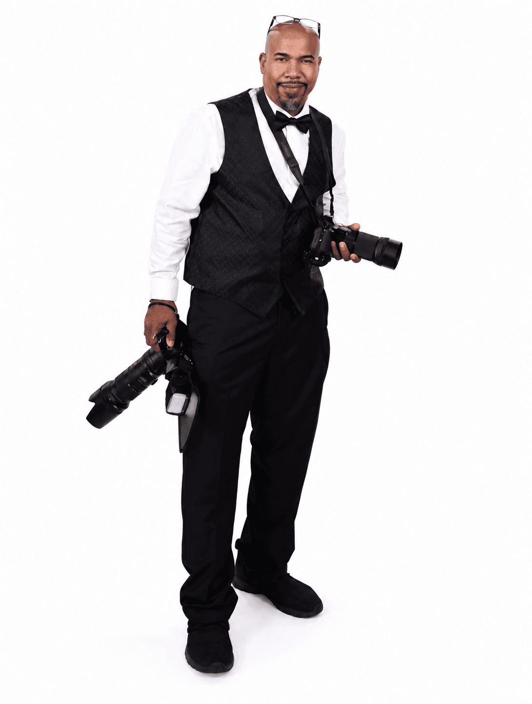 Wyatt Clark in a black vest and bow tie holding two professional cameras